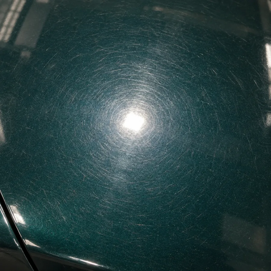 Close-up of a green hood covered in fine swirl marks